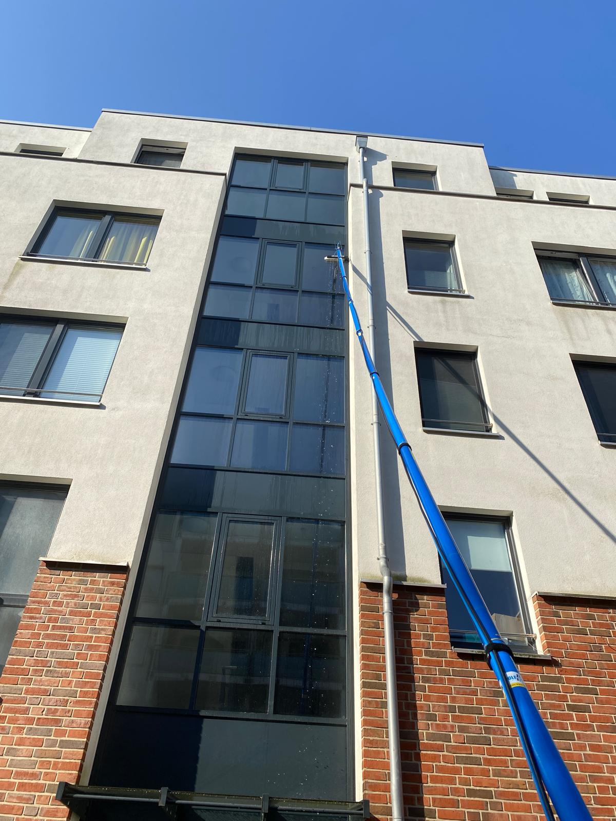 Glasreinigung mit einer Teleskopstange an einem hohen Gebäude